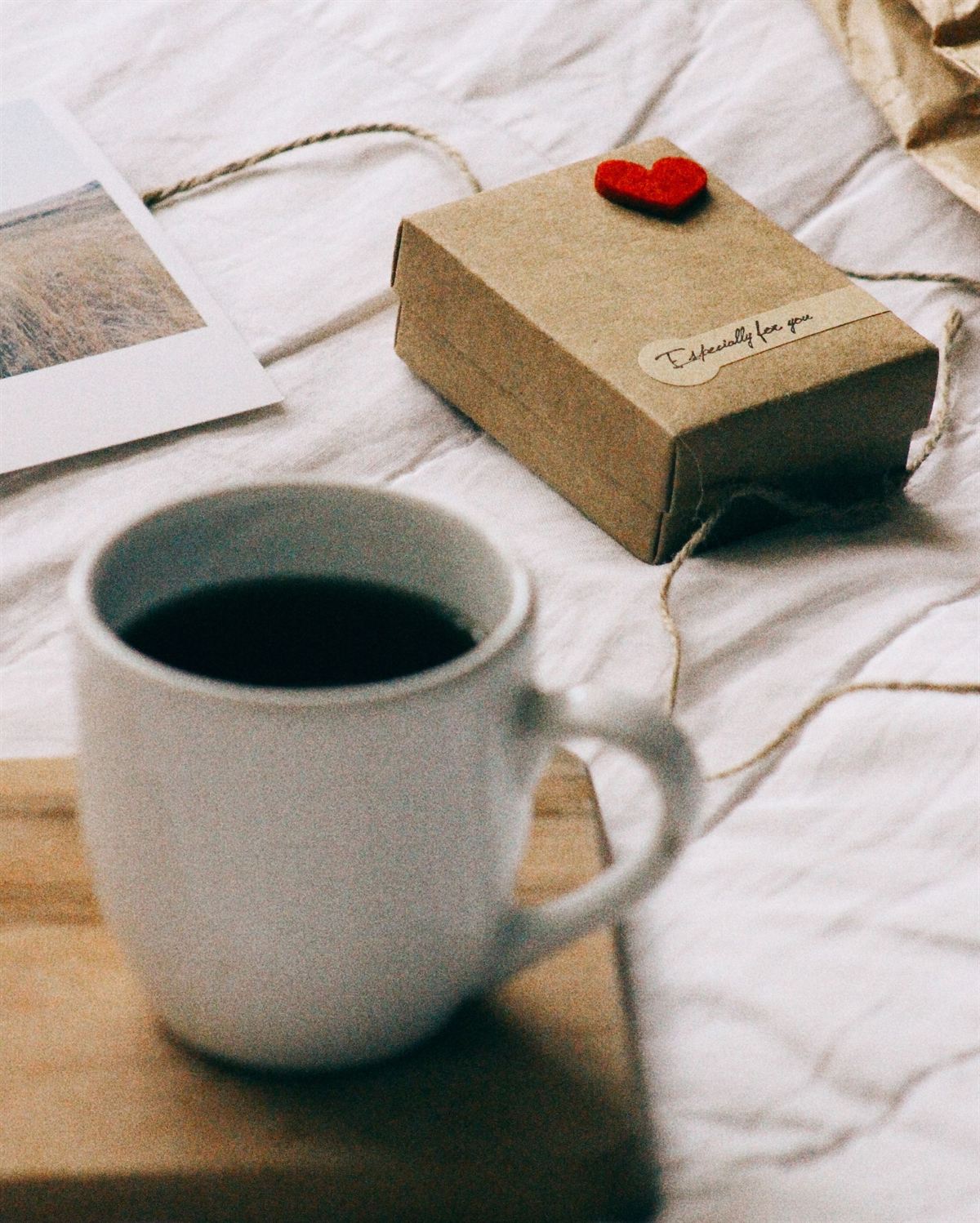 En kopp kaffe bredvid ett litet paket på en säng